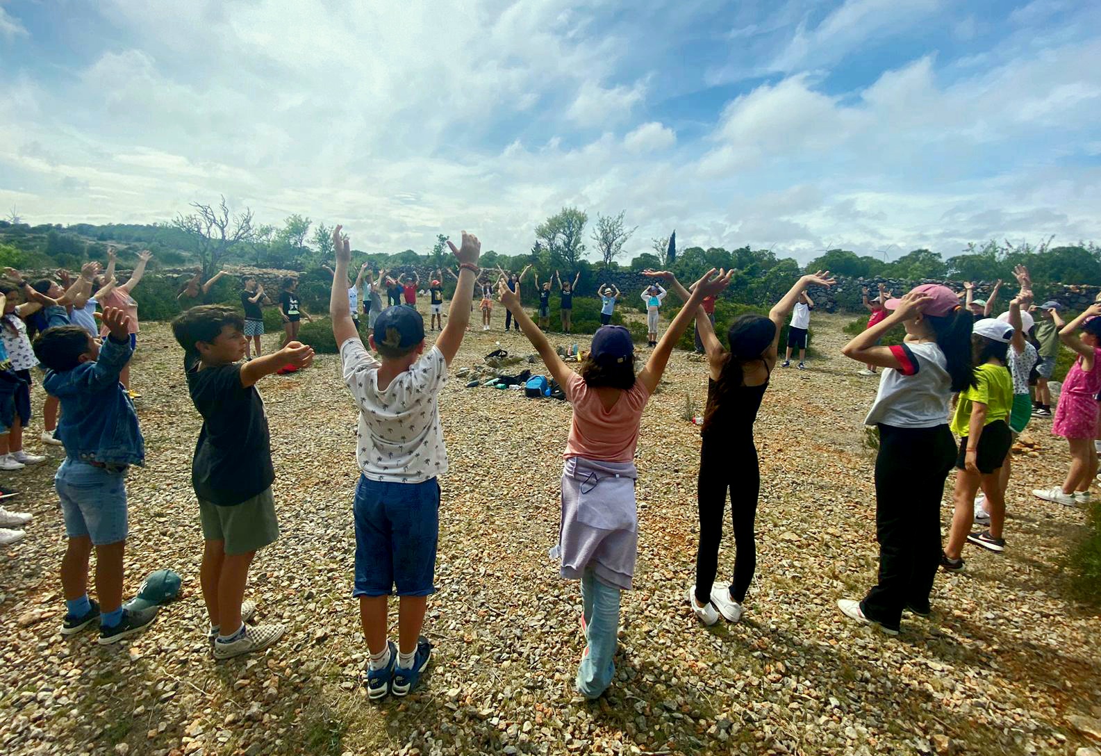 Groupe d’enfants dans la nature, bras levés