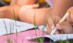 Petites mains et cahiers dans l’herbe